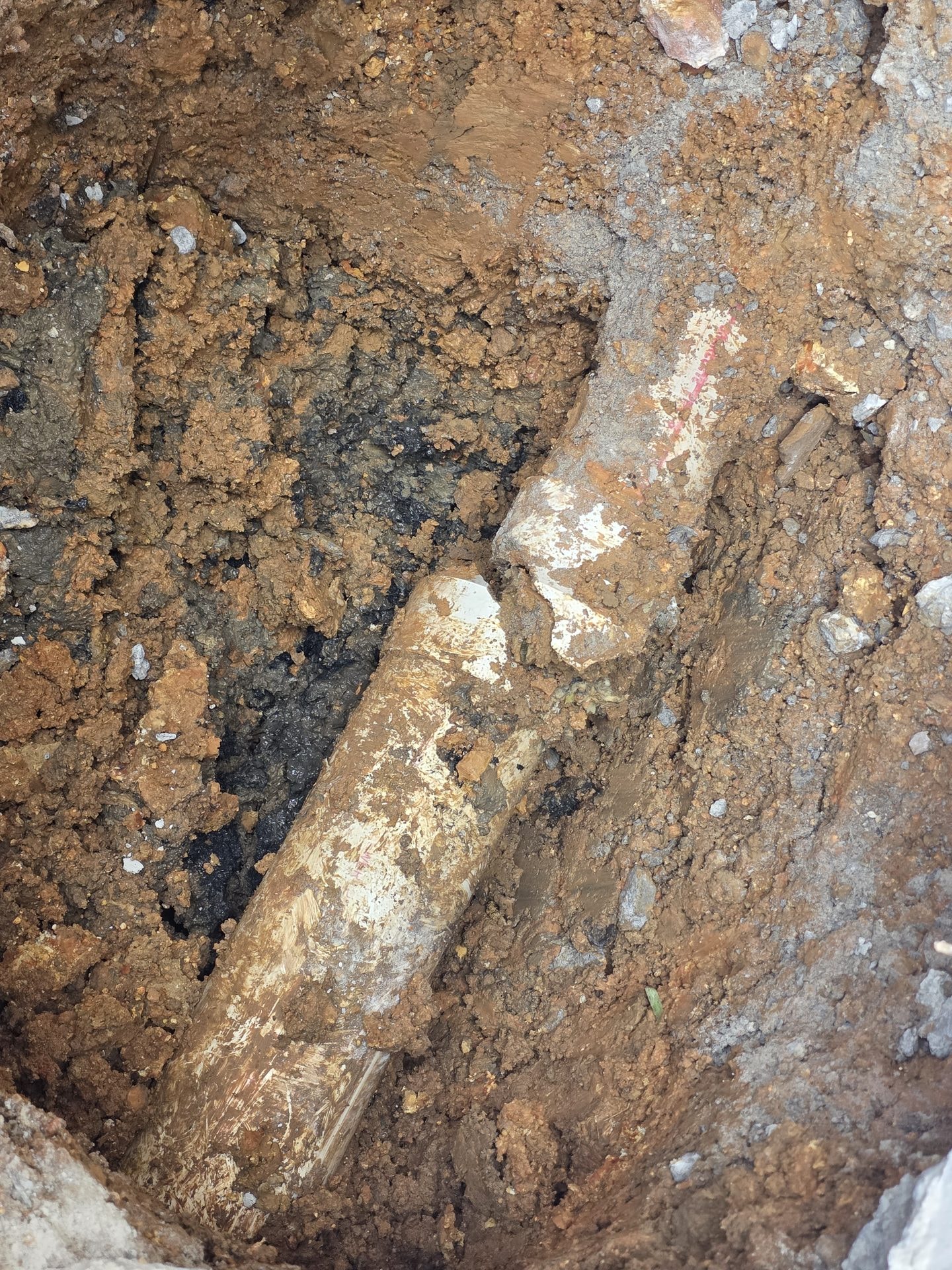 Close-up of a repaired sewer pipe joint in an open trench